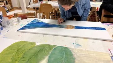 Person paints abstract blue and green artwork.