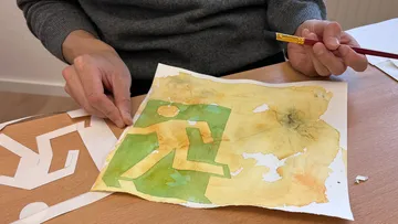 Person, die ein grünes Ausgangsschild auf Papier malt.