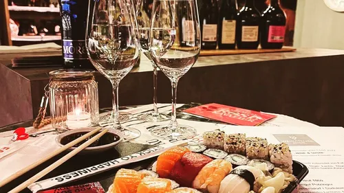 Sushi platter with wine glasses on table.
