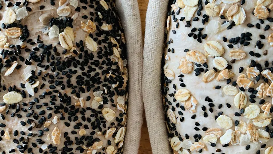 Two loaves of bread with seeds and oats.