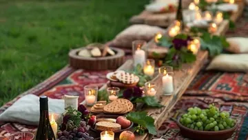 Picknick im Freien mit Kerzen, Obst und Kissen.