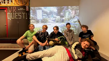 Group of young people posing in VR gaming room.