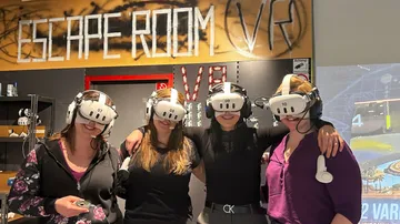 Four people wearing VR headsets in escape room.
