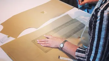 Person, die mit Lineal auf braunem Papier zeichnet.