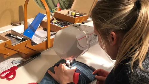 Person sewing fabric with a machine.