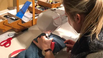 Person sewing fabric with a sewing machine.
