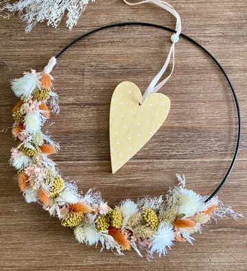 Blumenkranz mit Herzdekor auf Holz.