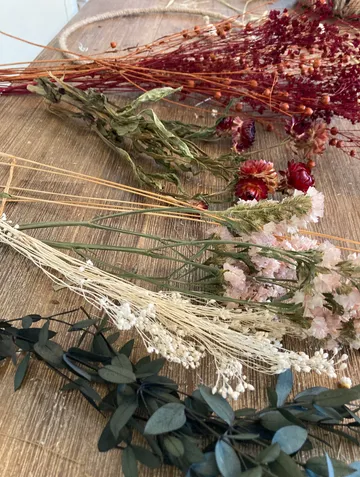 Verschiedene Trockenblumen auf einem Holztisch.