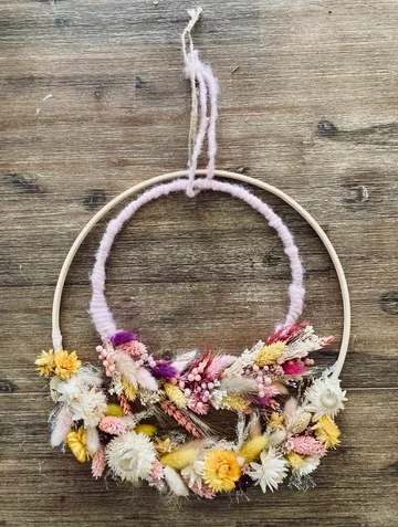 Blumiger Traumfänger mit getrockneten Blumen auf Holz.