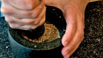 Hands using mortar and pestle, grinding spices.