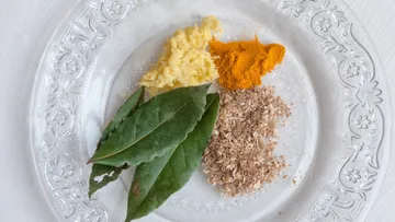 Spices and bay leaves on a clear plate.