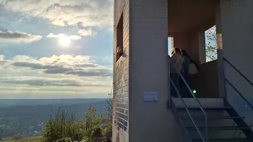 Menschen stehen auf einem Aussichtsturm mit Blick auf die Landschaft.