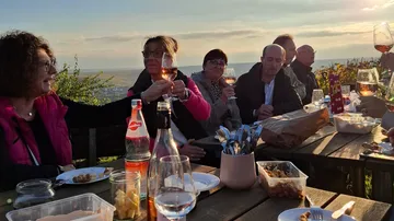 Leute, die beim Picknick im Freien mit Wein anstoßen.