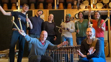Gruppe mit Schlägeln, lächelnd im Musikzimmer.