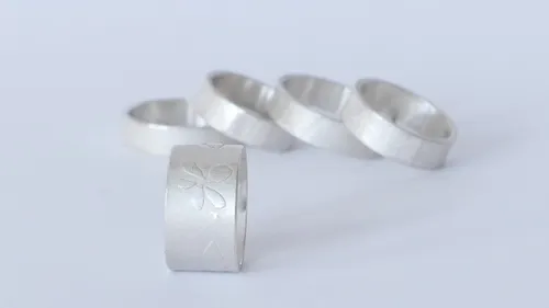 Five silver rings with a floral design.