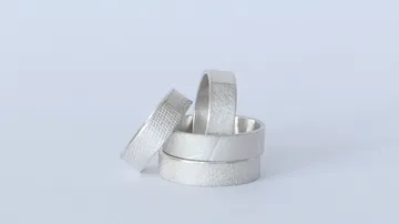 Four silver rings stacked on surface.