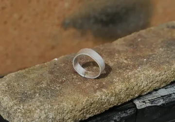 Silver ring resting on a stone surface.