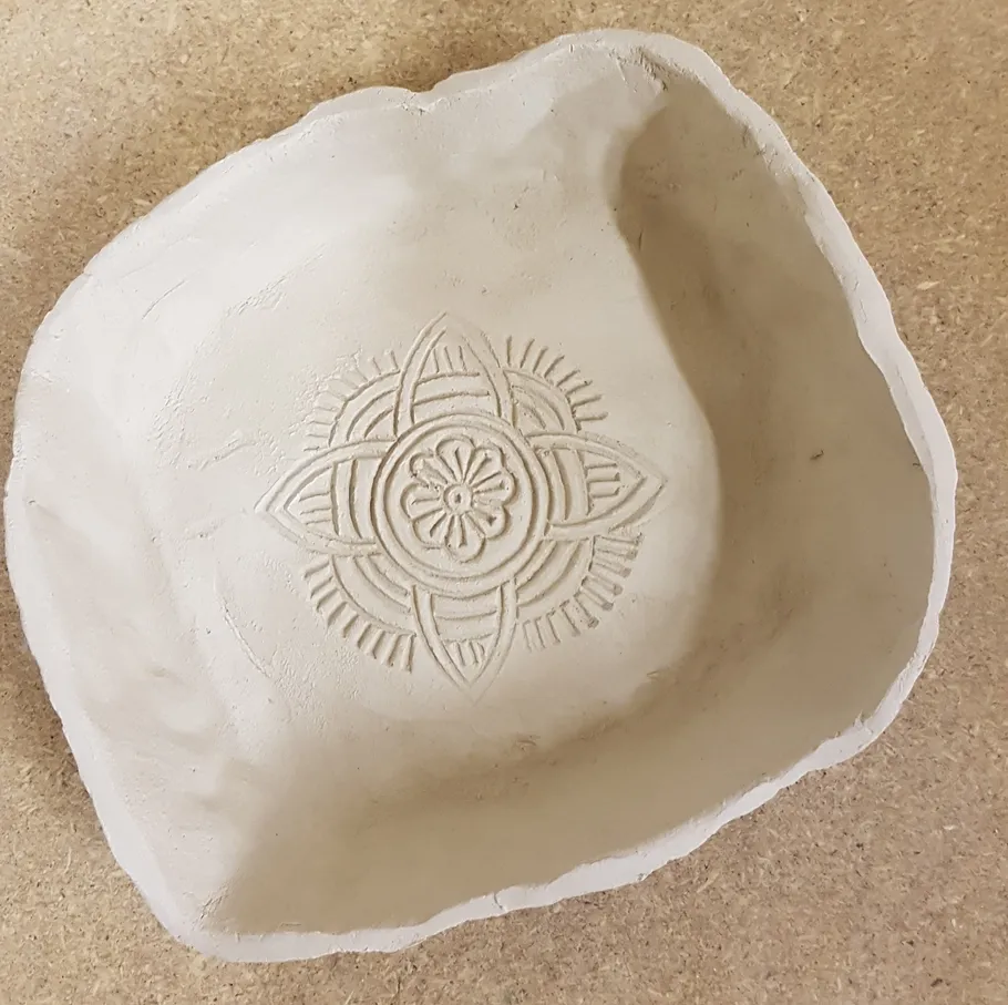White clay bowl with intricate etched pattern.