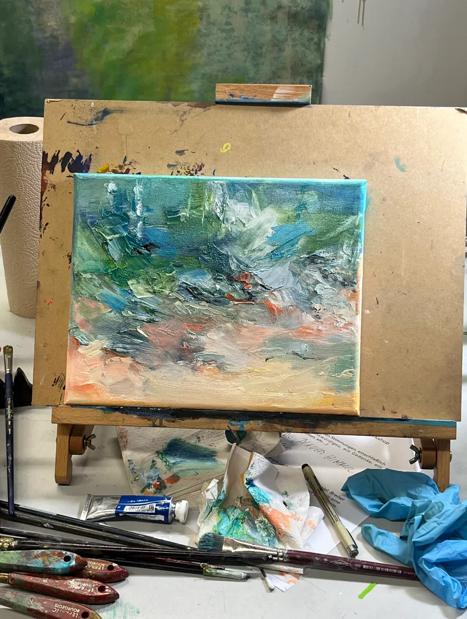 Abstract painting on easel with paint supplies.