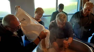 Gruppe, die Zutaten in einen großen Brühtopf gibt.