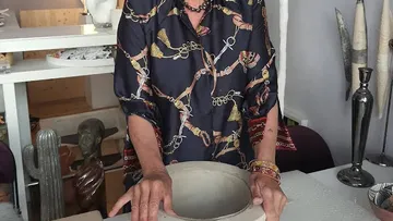 Person shaping clay pot in art studio.