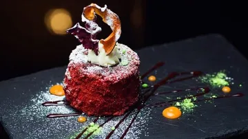 Decorative red velvet cake on slate plate.