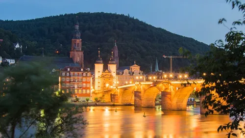 Beleuchtete Brücke über den Fluss in der Abenddämmerung, Hangkulisse.