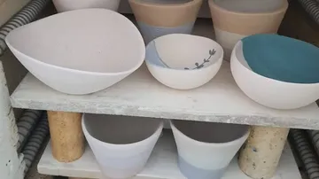 Handcrafted ceramic bowls on wooden shelves.