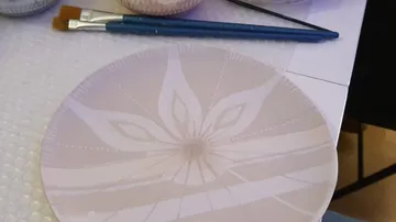 Decorative plate with paintbrushes on table.