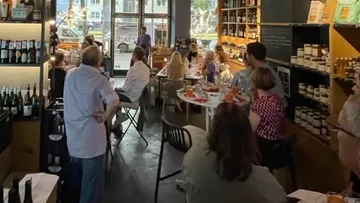 People dining at a cozy restaurant with wine shelves.