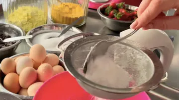 Mehl von Hand über die Rührschüssel sieben, Küchentisch.