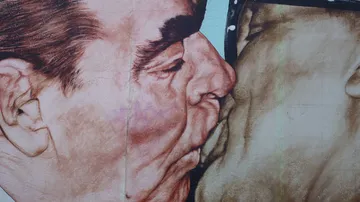 Gemälde von zwei Männern, die sich eng küssen.