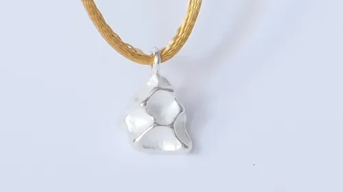 Silver pendant on yellow string.