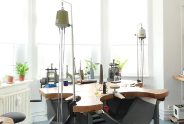 Arbeitsbereich zur Schmuckherstellung mit Werkzeugen und Pflanzen.