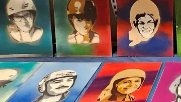 Colorful helmet-themed stencil portraits on display table.