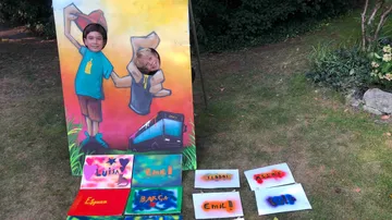 Kids' faces in cutouts, painted backdrop, lawn.