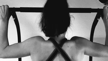 Person doing pull-up on indoor bar.