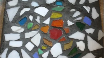 Colorful mosaic pieces embedded in dark cement.