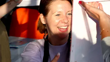 Smiling woman greeted warmly with papers.