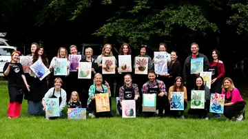 Gruppe von Menschen, die im Freien Bilder in der Hand halten.