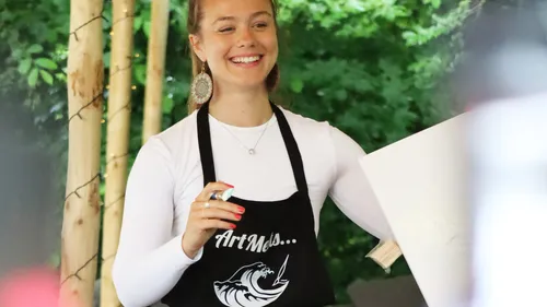 Person in Schürze, die Pappe im Freien hält.