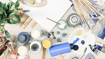 Art supplies on a table with plants nearby.