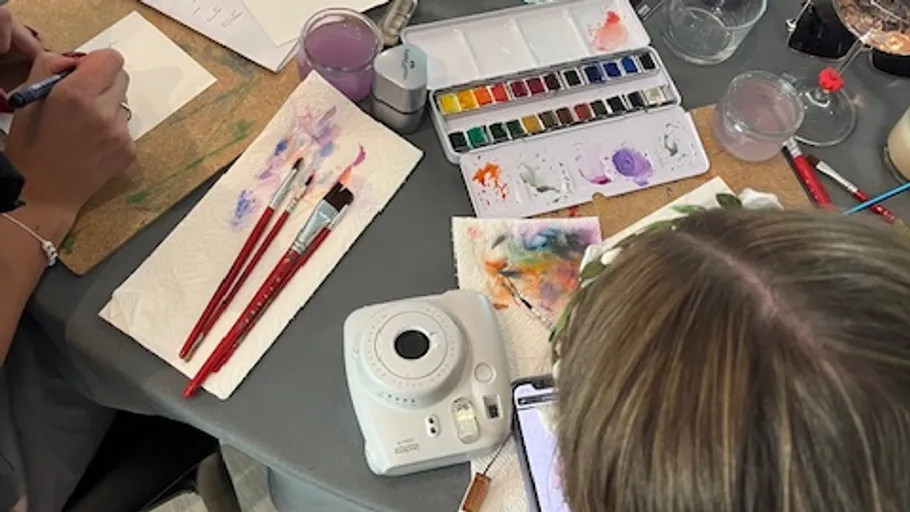 People painting at table with brushes and watercolors.