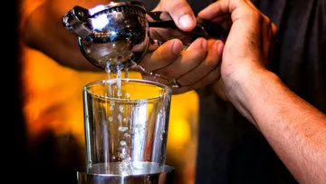 Person squeezing juice into a glass indoors.