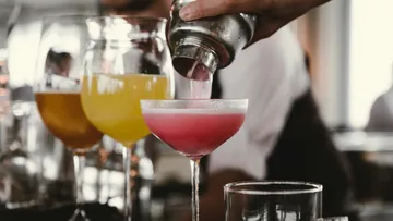Pink cocktail poured from shaker into glass.