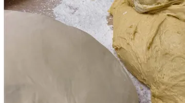 Zwei Teiglinge auf einer bemehlten Oberfläche.