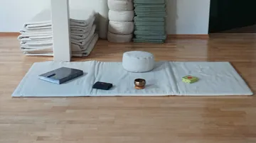 Meditation cushion on mat with books.