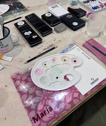 Art supplies on a table with paint palette.