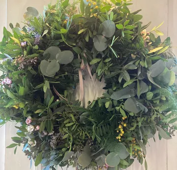 Greenery wreath with pink flowers on wall.