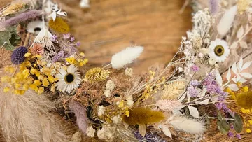 Wreath of dried flowers on wood surface.